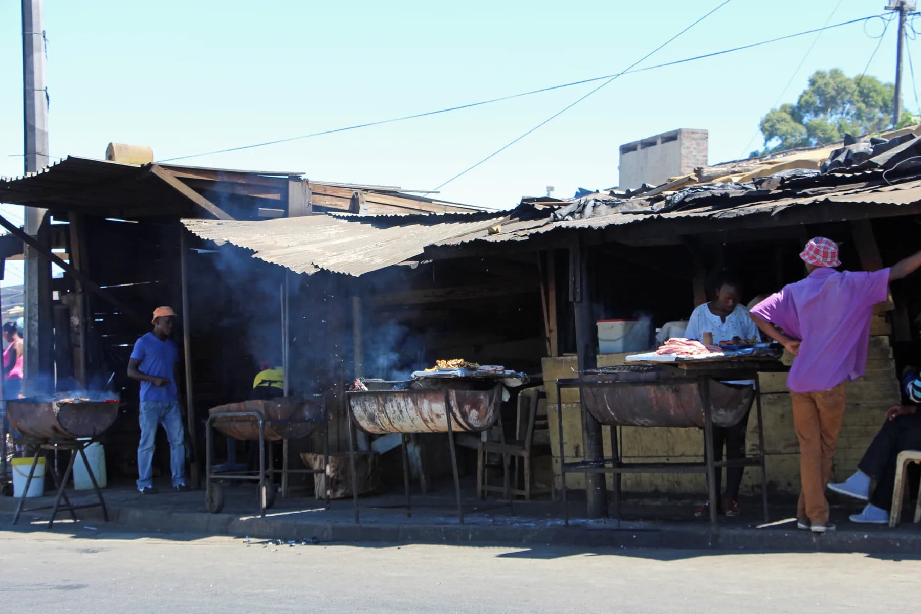 A pavement braai in Kayamandi, smoke rising off the grills
