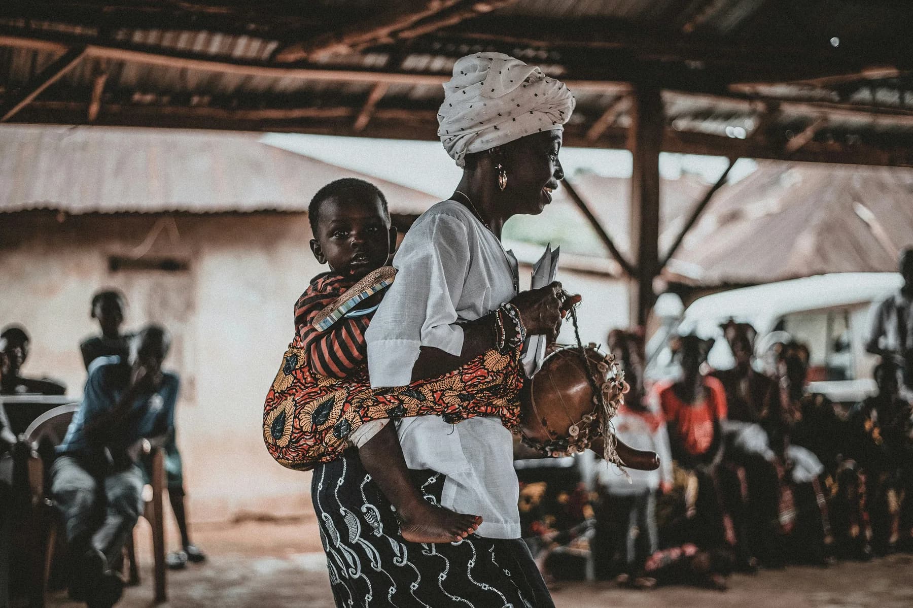 A woman carrying a child on her back at a community gathering