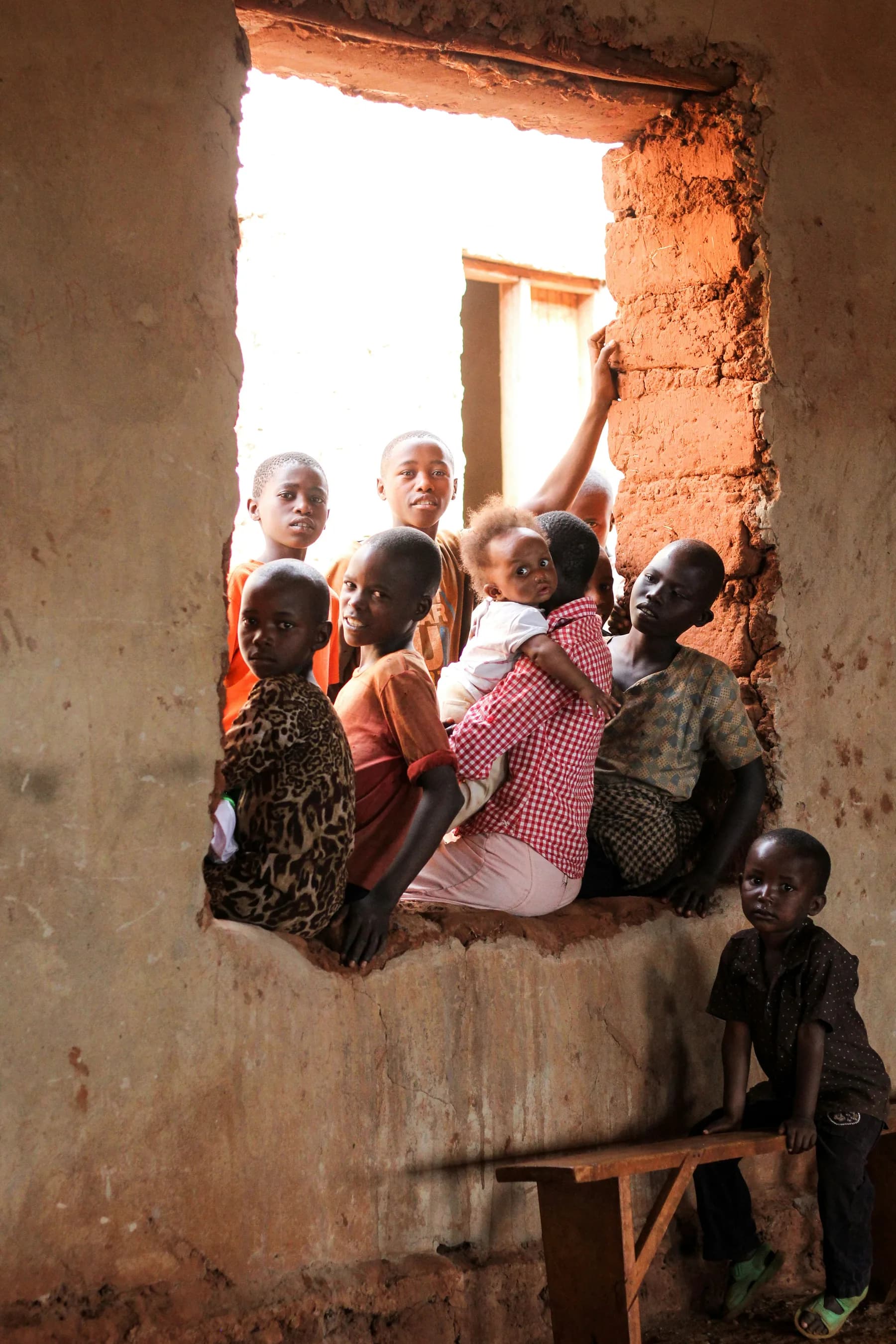 Children gathered in a window opening, looking out together