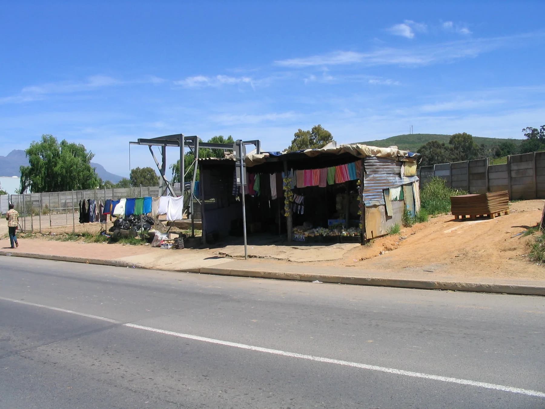 A roadside stall on a Kayamandi corner, washing strung along the fence