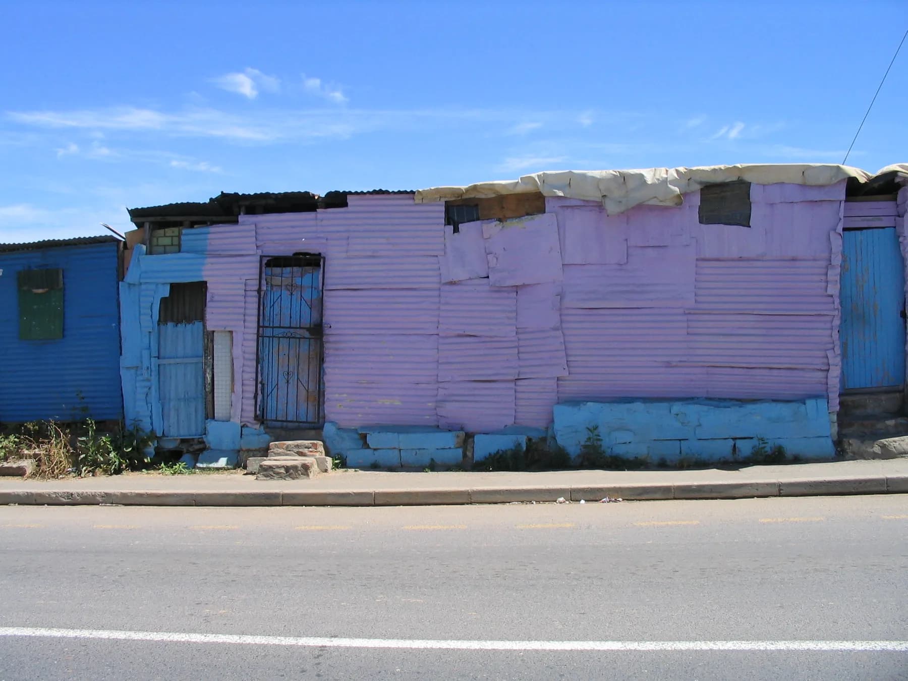 A row of painted corrugated-iron homes along a Kayamandi street