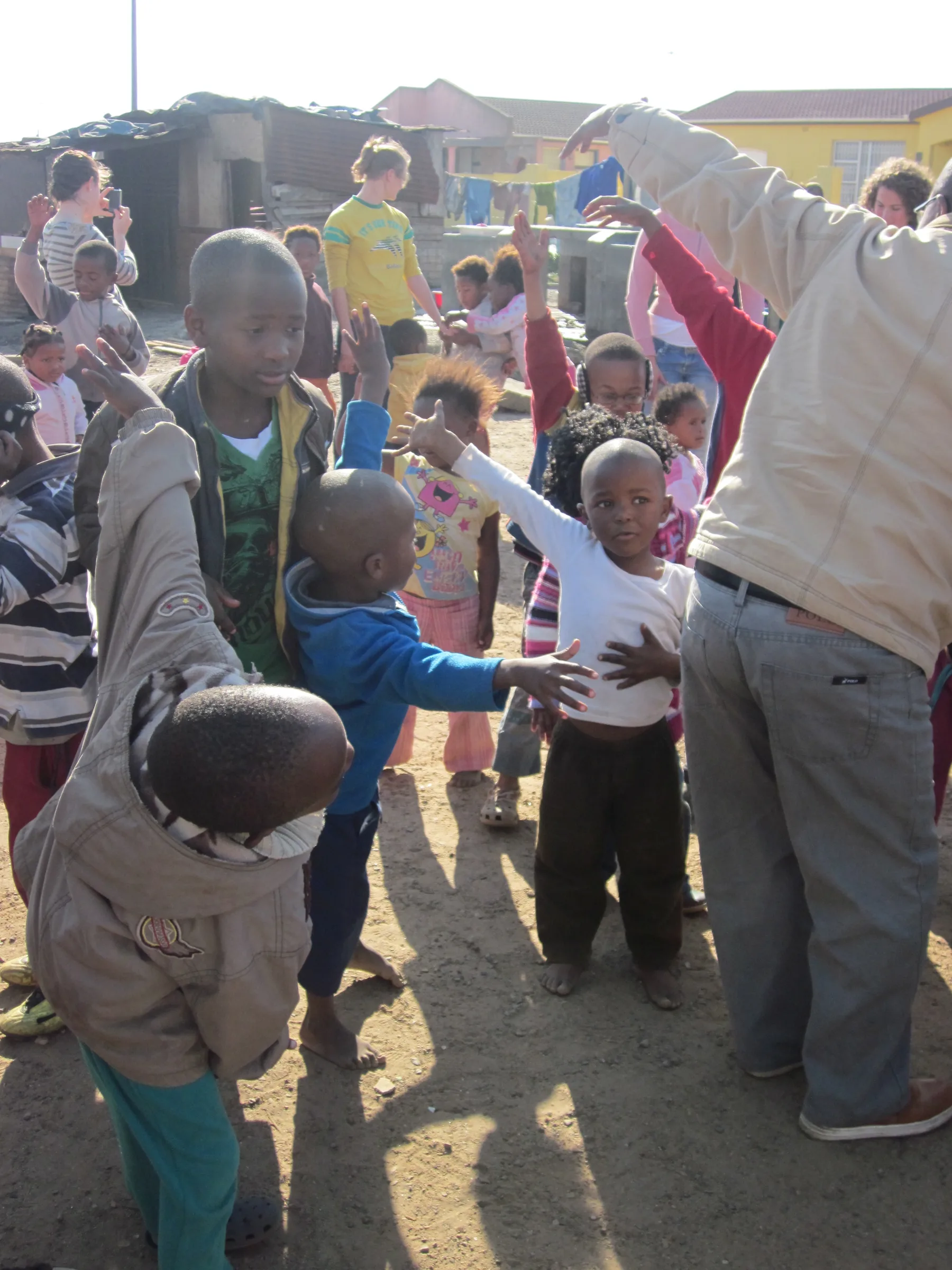 Children with their hands in the air, playing a game together on open ground