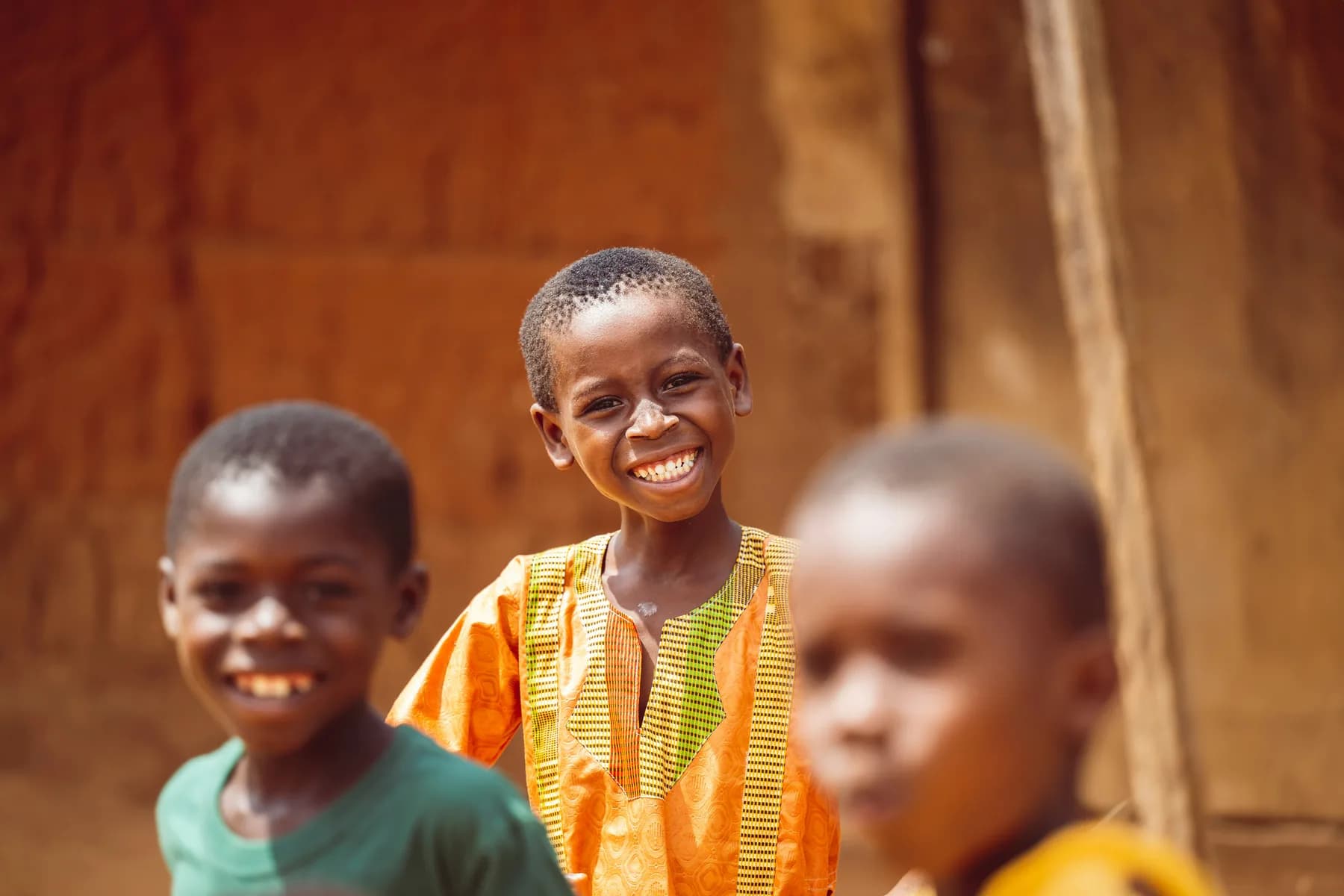 A boy laughing with friends outside a timber building