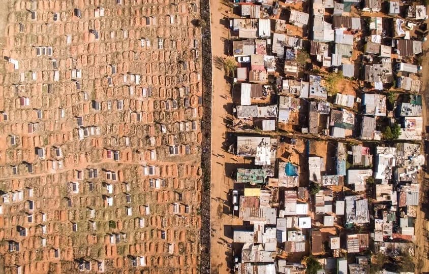 Formal housing and an informal settlement meeting along a single line, seen from the air